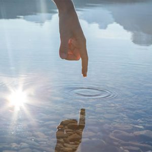 Refection of a persons finger rippling the water - creativity