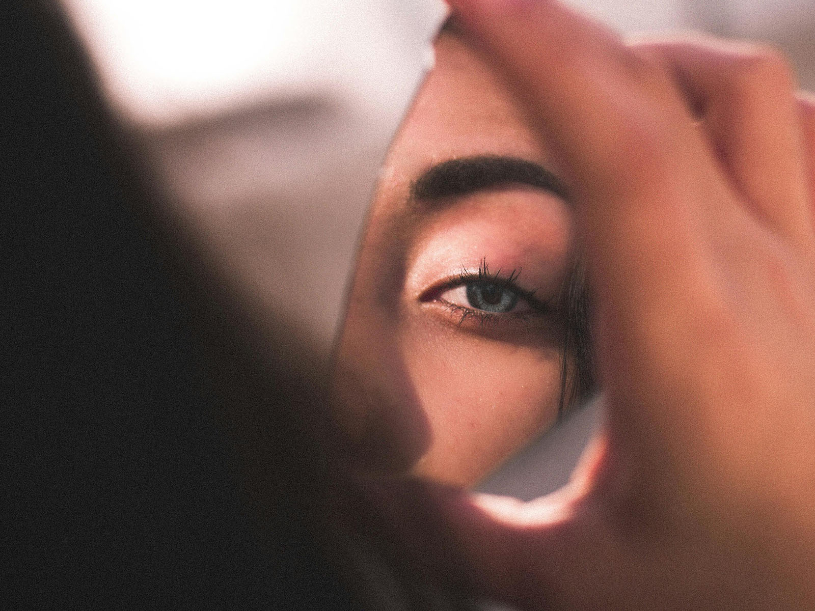 Woman looking into broken mirror