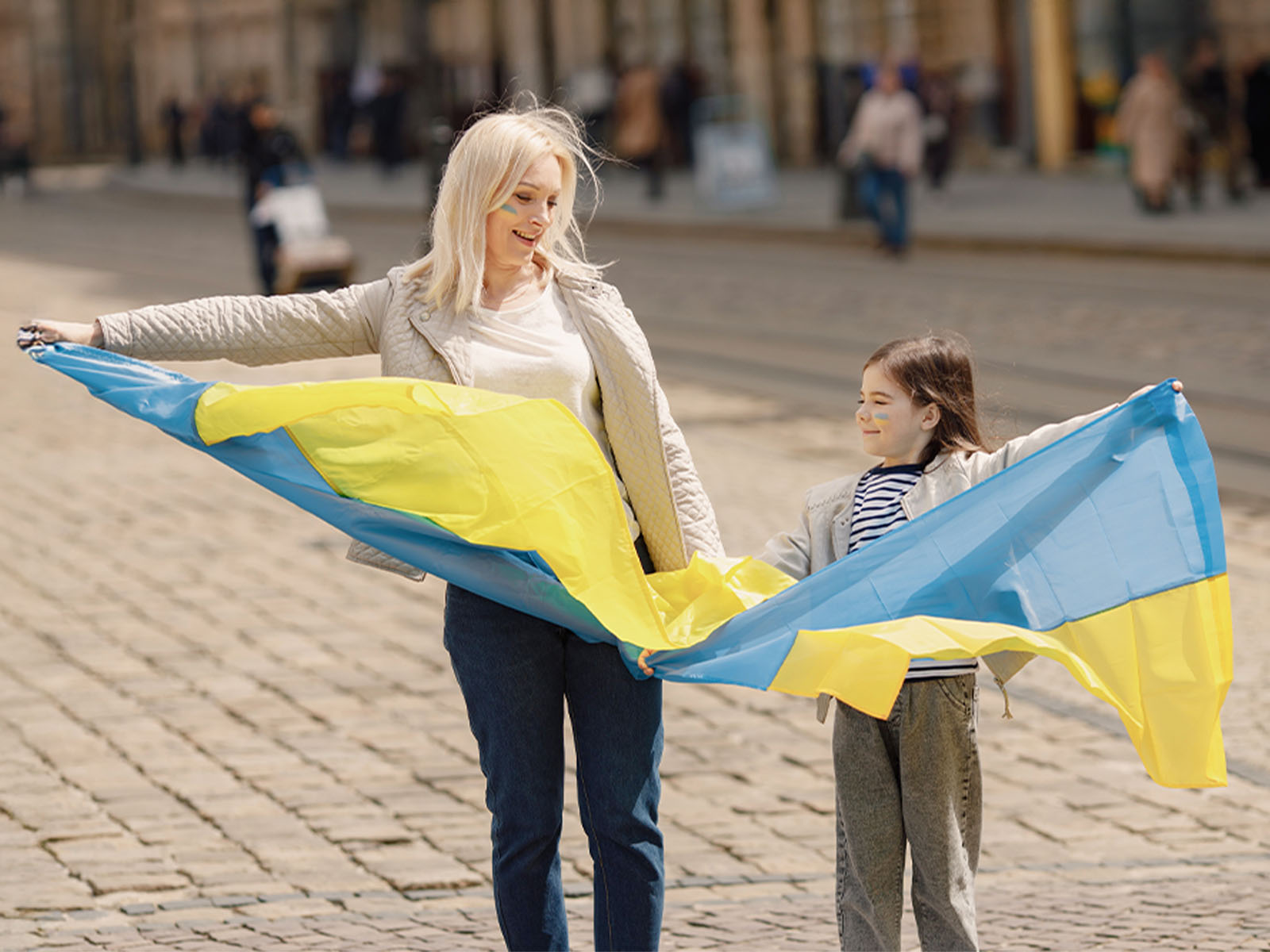 photo of mother and her daughter standing with a Ukrainian flag